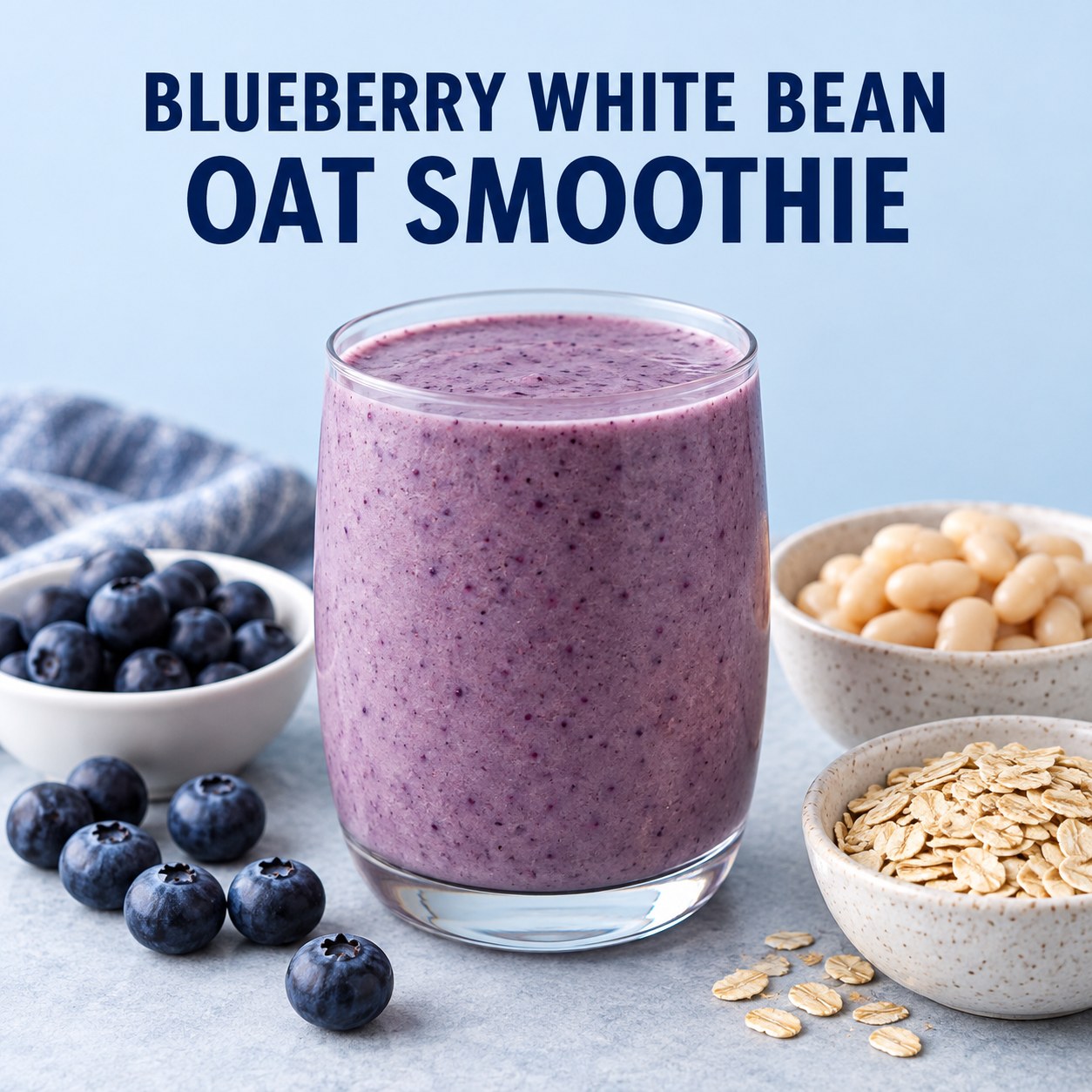 Purple blueberry smoothie beside blueberries, a small bowl of cooked white beans, and oats on a pale blue table.
