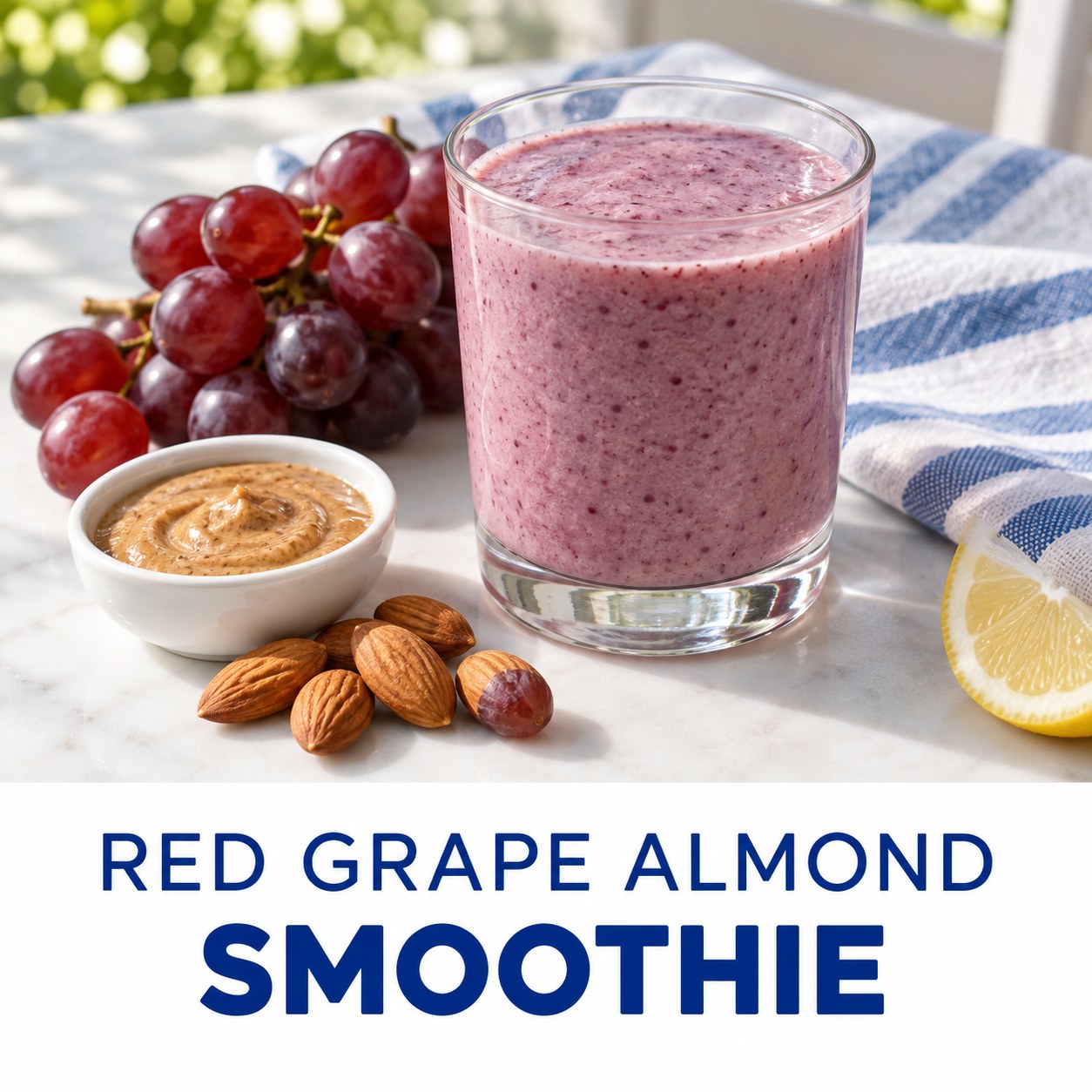 Soft purple grape almond yogurt smoothie beside red grapes and almond butter on a white-and-blue table with readable Red Grape Almond Smoothie text.