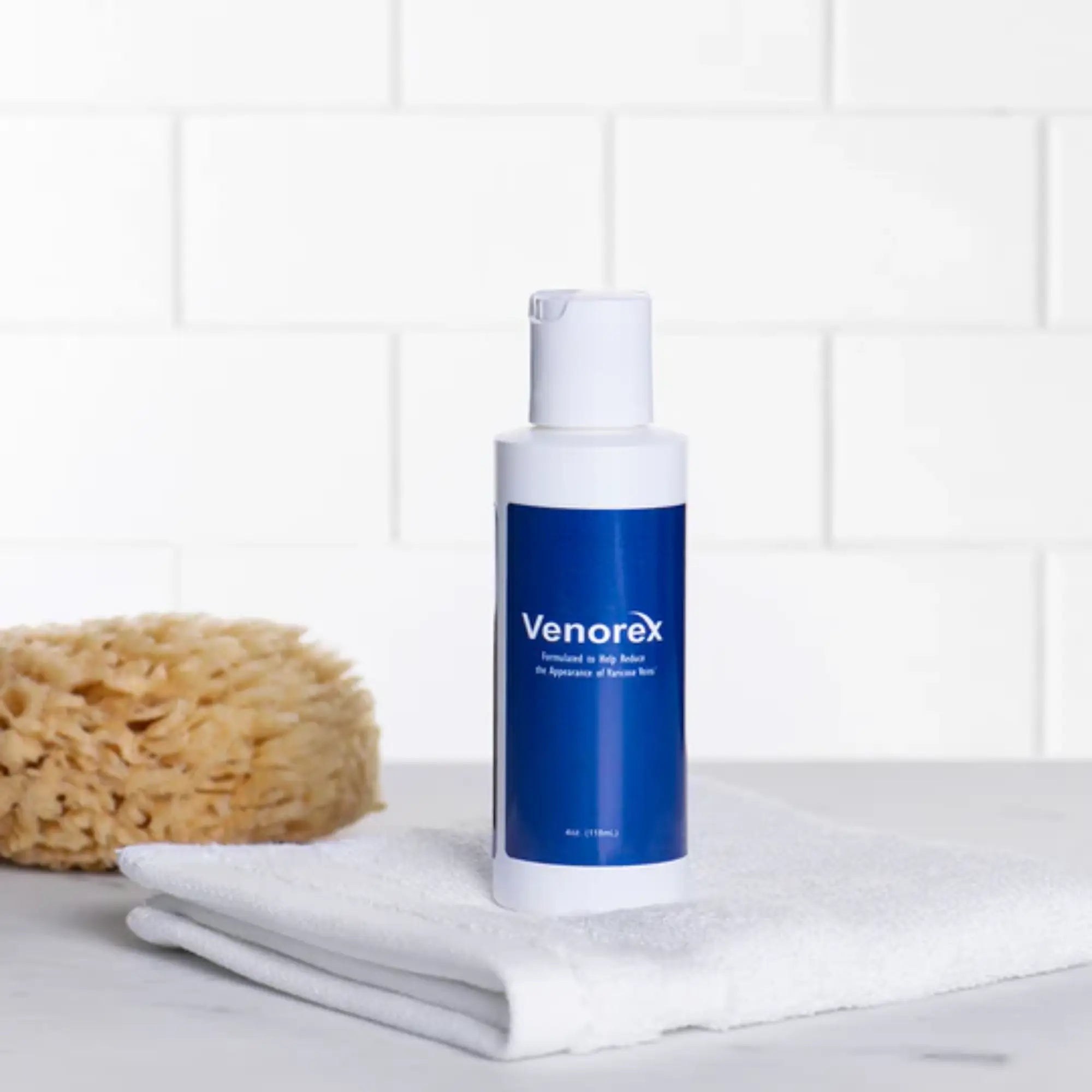 Venorex topical cream in a white bottle with a blue label beside towels and a sponge